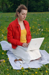 Frau auf einer Blumenwiese mit Laptop