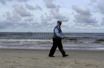 Ein aelterer Mann laeuft am Strand entlang