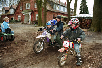 Mutter mit ihren zwei Kindern faehrt Motocross im Garten  Norddeutschland
