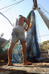 Cala Figuera  Fischer saeubert ein Fischernetz