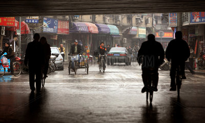 Shanghai  Fahrradfahrer auf regennasser Strasse