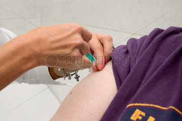 Berlin  Deutschland  Aerztin setzt Spritze in den Oberarm eines Patienten