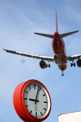 Berlin  Deutschland  ein tief fliegendes Flugzeug fliegt ueber eine Uhr