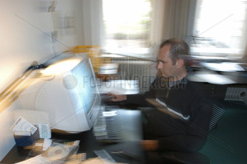 Mann sitzt am Computer bei der Arbeit