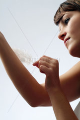 Berlin  junge Frau streichelt ihren Arm mit einer Feder