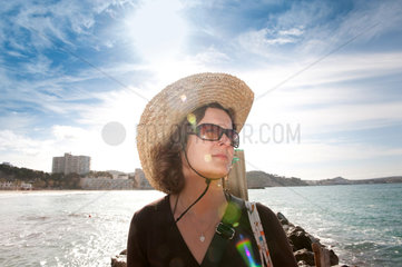 Peguera  Mallorca  Spanien  eine Frau mit einem Strohhut und Sonnenbrille am Strand