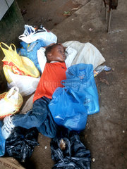 Ein Kind schlaeft auf der Erde in Swaziland