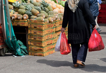 Frau mit Kopftuch und Einkaufstueten auf einem Markt