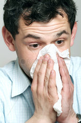 Mann niest in ein Taschentuch