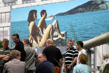 Berlin  Deutschland  Touristen vor einem grossen Werbeplakat an einer Hausfassade