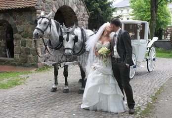 Berlin  Deutschland  junges Brautpaar mit einer Kutsche vor einer Kirche