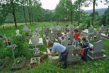 Frau mit Maedchen bei der Grabpflege  Sued-Ostpolen