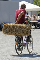 Hannover  Deutschland  Fahrradfahrer transportiert einen Strohballen