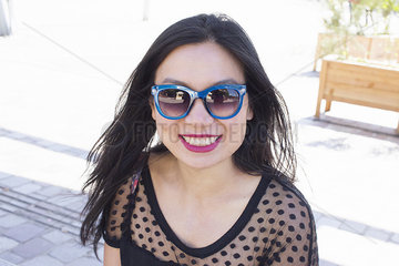 Woman wearing sunglasses  smiling cheerfully  portrait