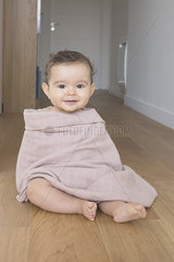 Baby sitting on floor  wrapped in a blanket  portrait