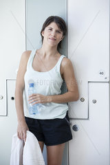 Woman relaxing in locker room with bottle of water  portrait
