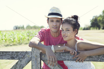 Young couple learning against wooden fence  portrait