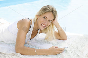 Woman using smartphone while relaxing at poolside  portrait