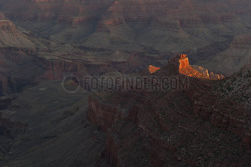 Evening sunlight illuminates a rock formation in the Grand Canyon  Arizona  USA