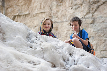 Children crouching on rock