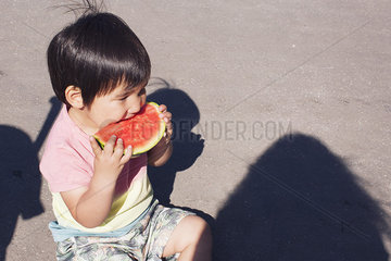 Little boy eating watermelon outdoors