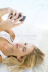 Woman using smartphone while relaxing at poolside  portrait