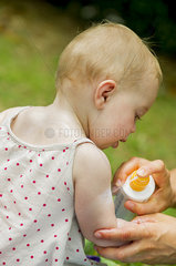 Parent spraying sunscreen on baby's arm
