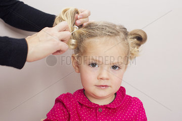 Little girl having her hair arranged in pigtails