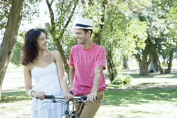 Young couple walking bicycle together