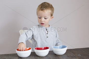 Little boy reaching into bowl