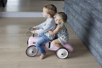 Young siblings riding on toy car together