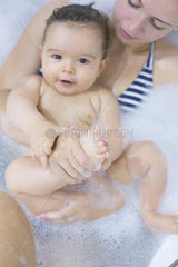 Mother and baby soaking in bathtub together