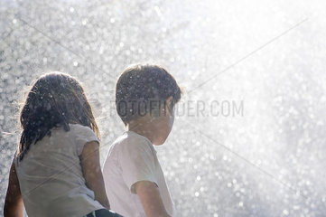 Children surrounded by spray from waterfall