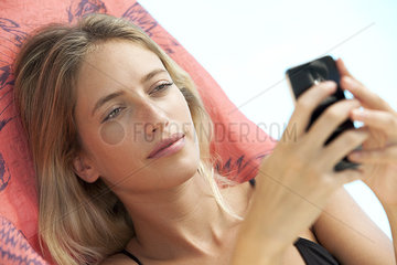 Woman relaxing on lounge chair using smartphone