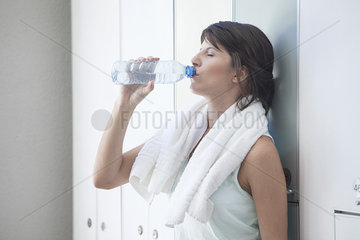 Woman drinking bottled water in locker room