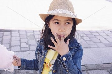 Girl eating cotton candy  licking fingers