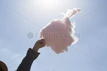 Hand holding cotton candy against blue sky