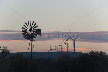 Tranquil view of an old-fashioned windmill and modern wind turbines against a twilit sky