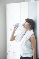 Woman drinking bottled water in locker room