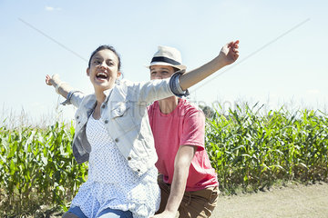Couple riding bike together  woman with arms outstretched