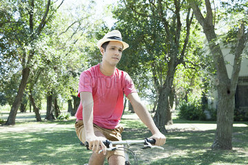 Young man riding bicycle through wooded countryside