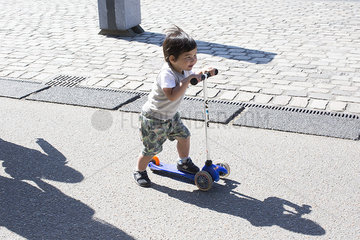 Little boy riding push scooter
