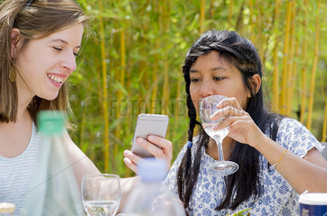 Women relaxing together outdoors  looking at smartphone