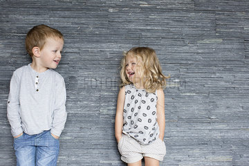 Children leaning against wall  smiling at each other