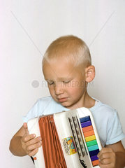 fuenfjaehriger Junge spielt auf seiner Ziehharmonika