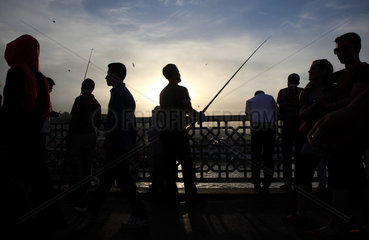 Istanbul  Tuerkei  Angler auf der Galatabruecke im Gegenlicht