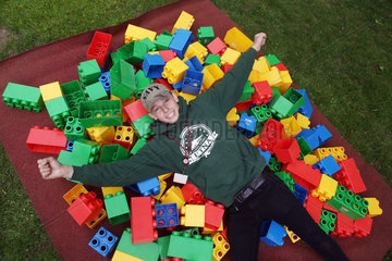 Hannover  Deutschland  Junge liegt lachend auf ueberdimensionalen Legosteinen