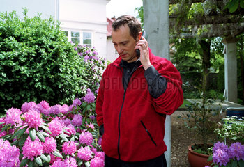 Mann telefoniert durch ein Schnurlostelefon in seinem Garten