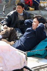 Peking  zwei Maenner ruhen sich auf ihren Lastenraedern aus