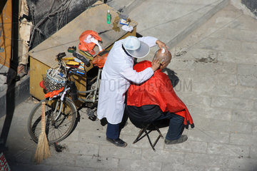 Peking  Friseur rasiert einem alten Mann des Kopf